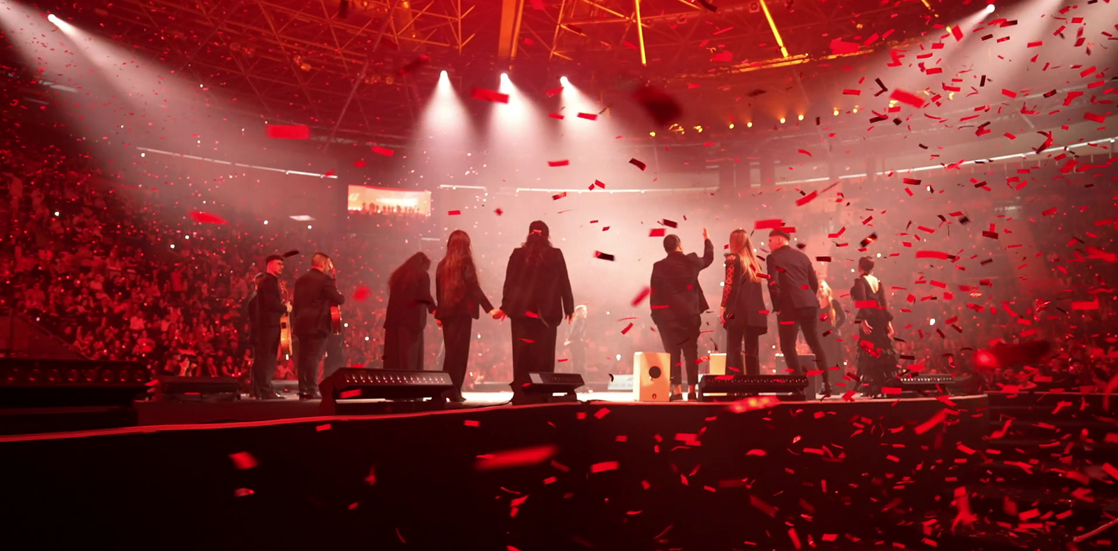 Live event finale with performers, red confetti and stage lighting